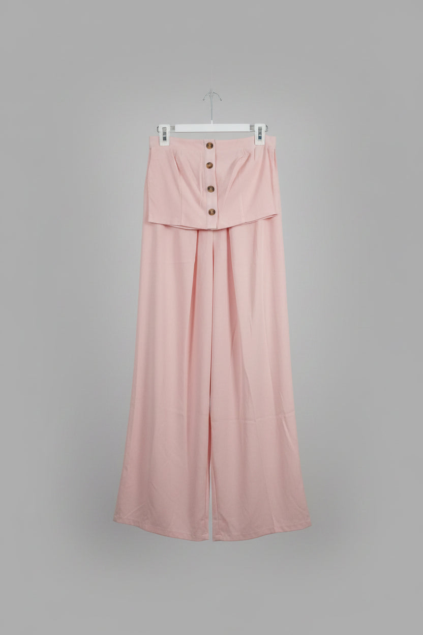 A light pink two-piece set consisting of a button-front top and matching wide-leg pants, hanging in an indoor room.
